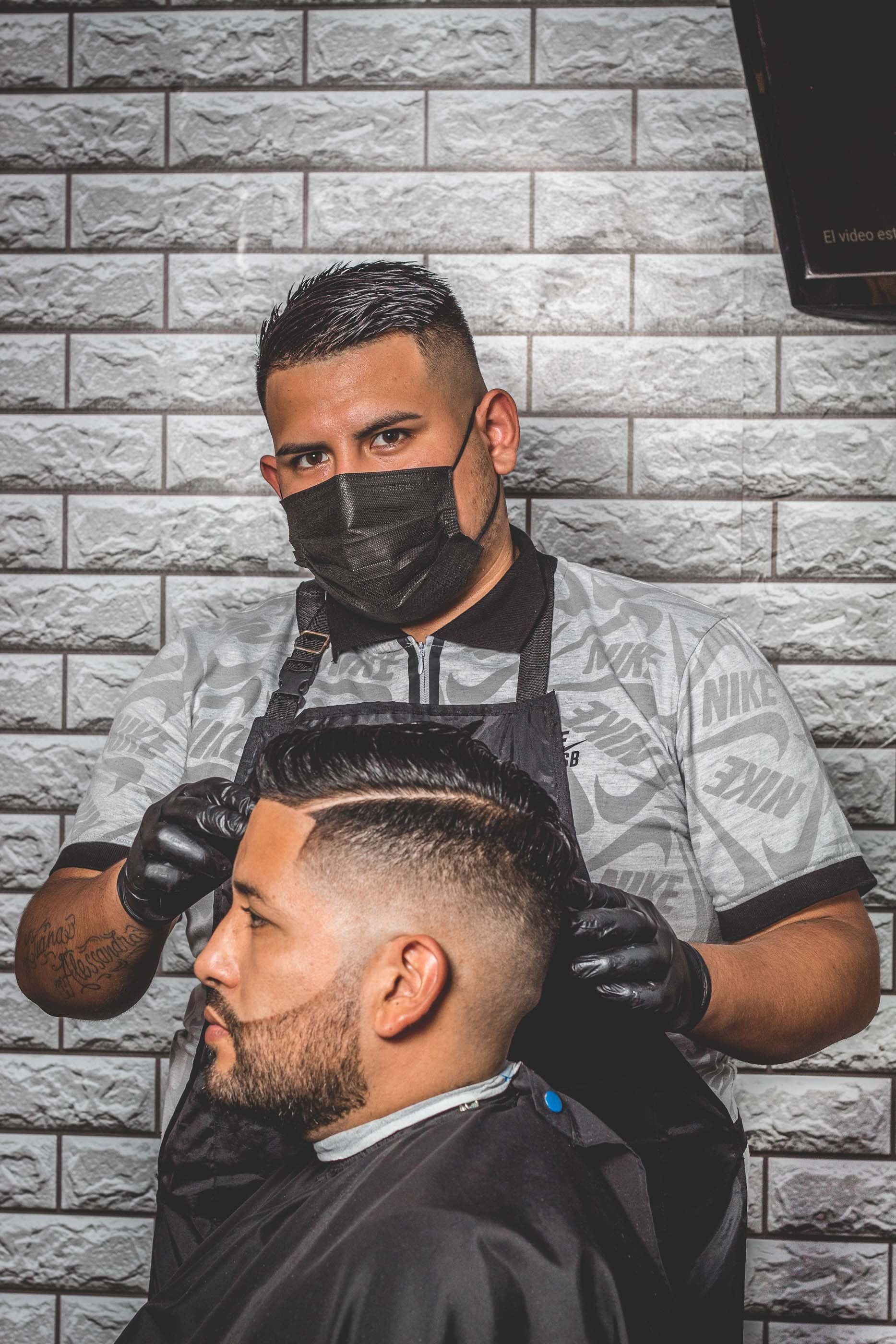 Un coiffeur avec son masque qui coupe des cheveux