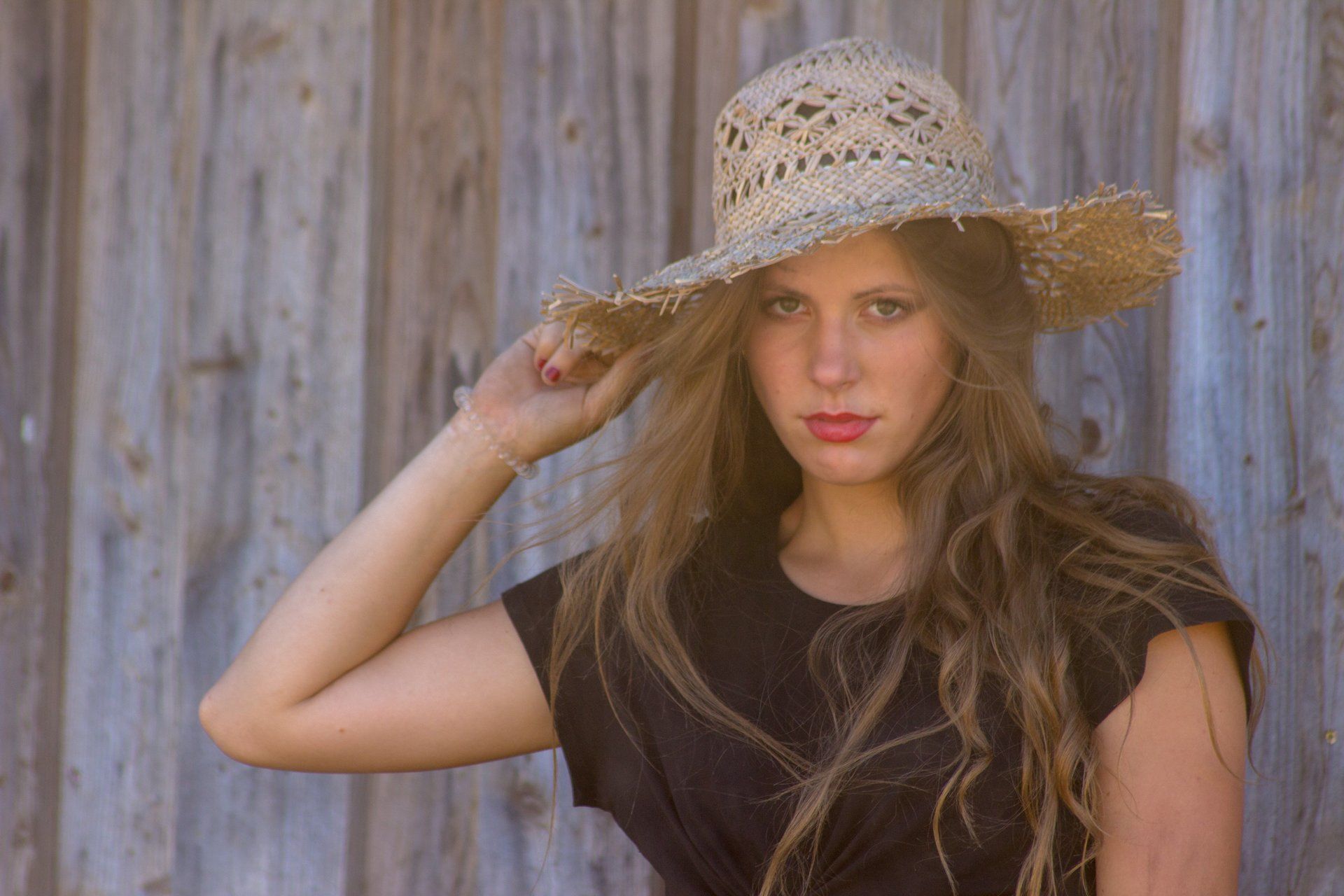 Portraitaufnahme von Girl mit Strohhut und langem Haar an Stallwand