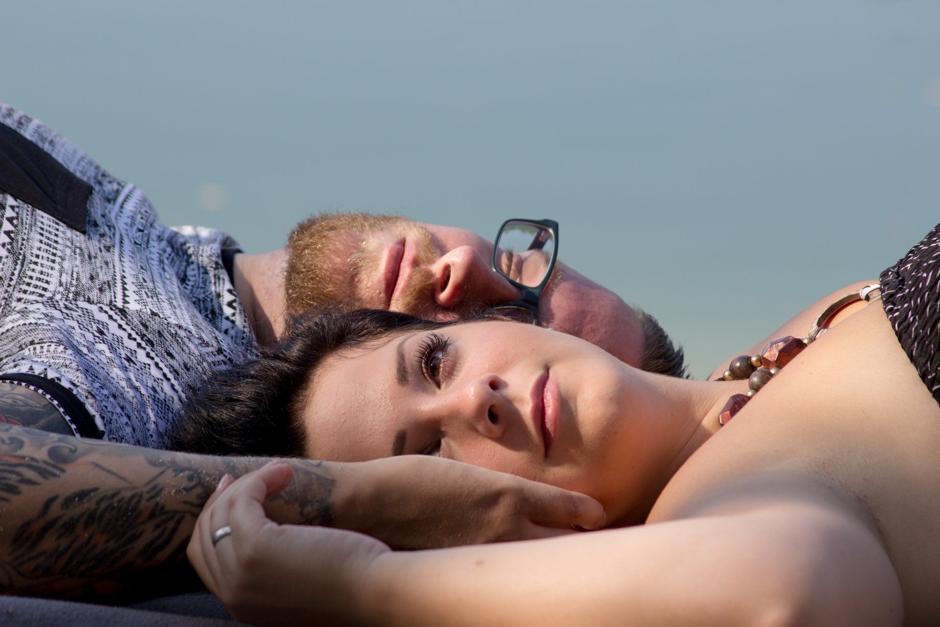 Portraitaufnahme vom Paar liegend am Strand, Himmel Hintergrund