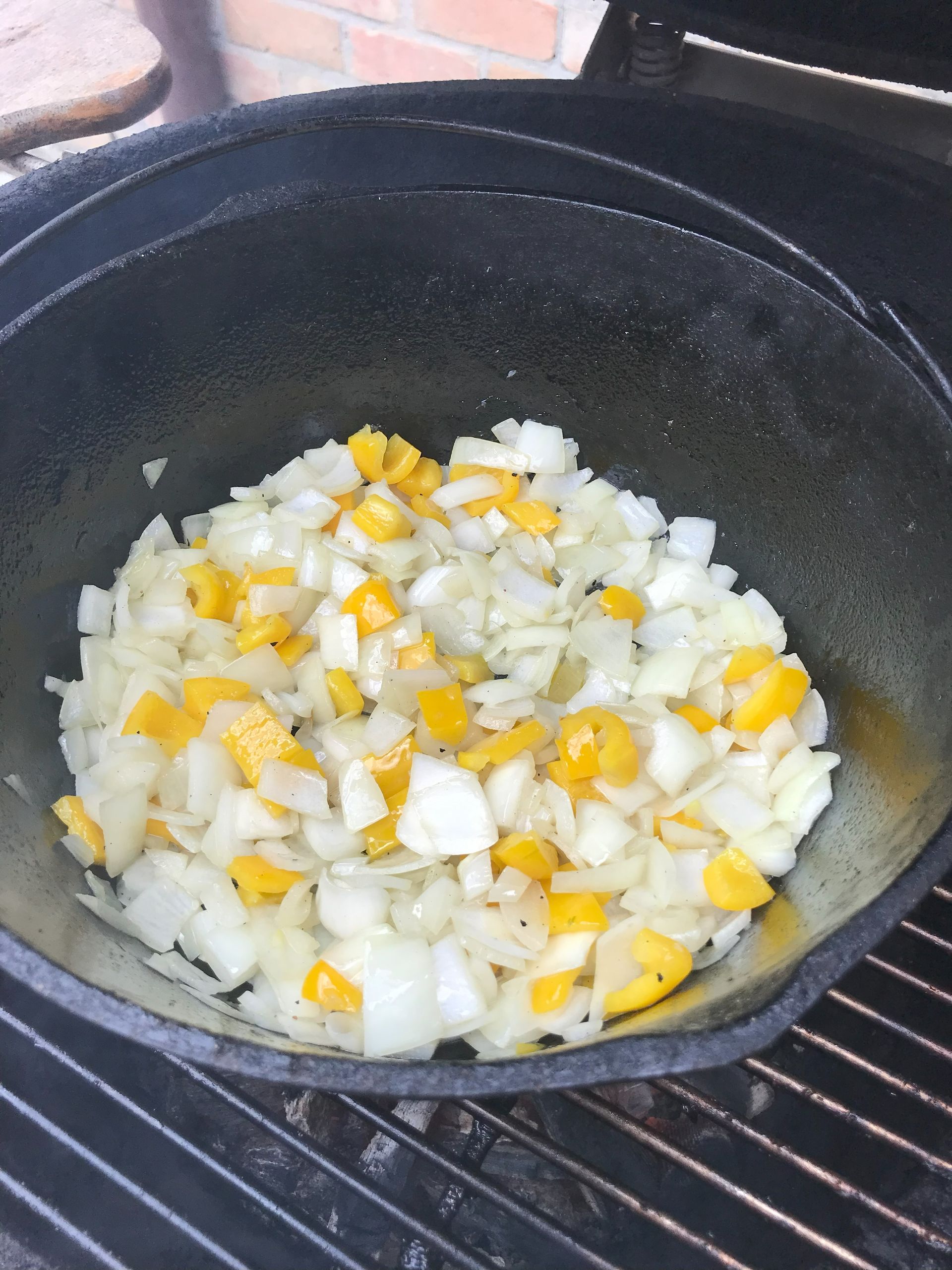 yellow bell peppers and onions in a cast iron pot on the grill