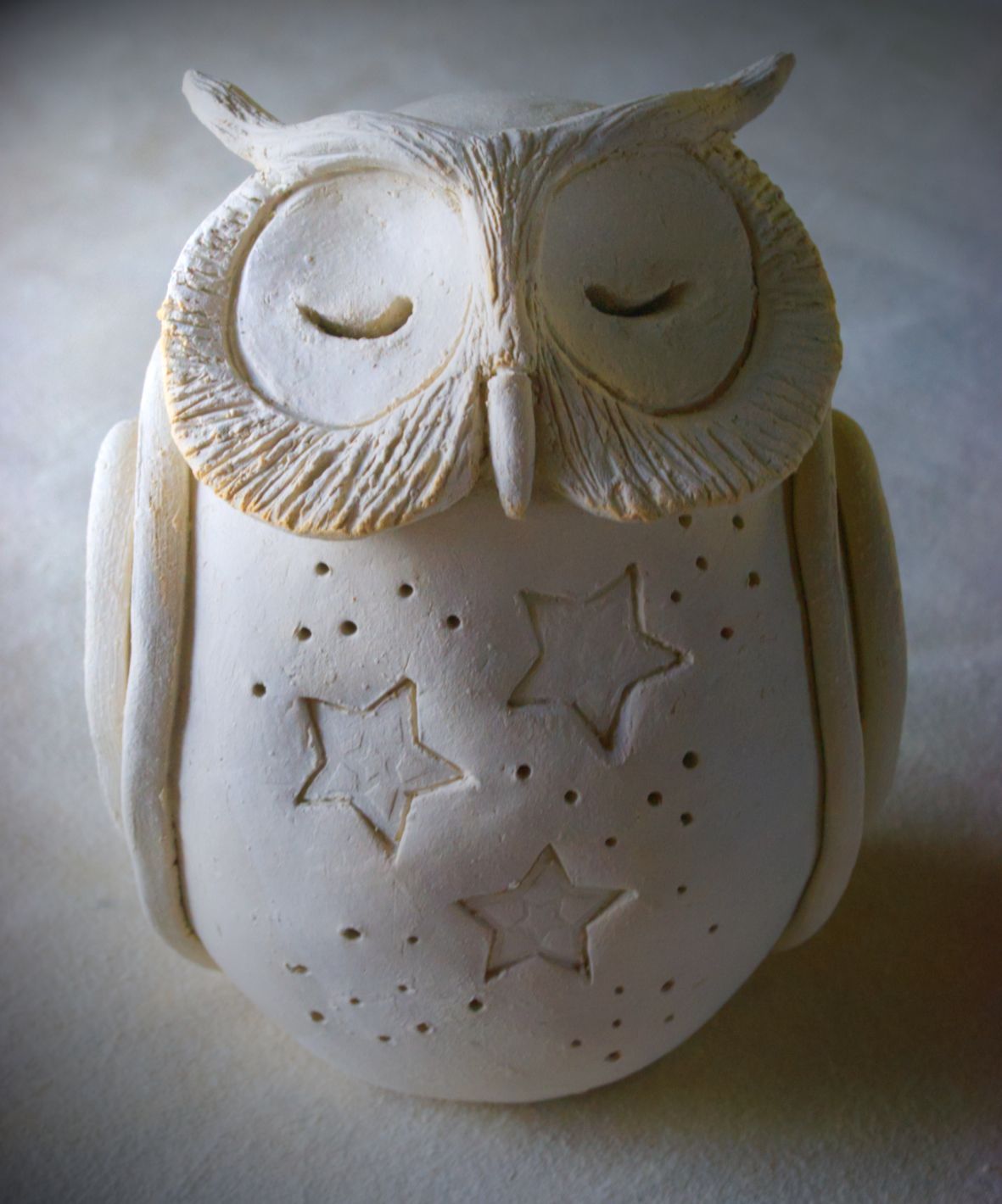 Ceramic cosmic owl made of earthen ware clay with stars on it's front.