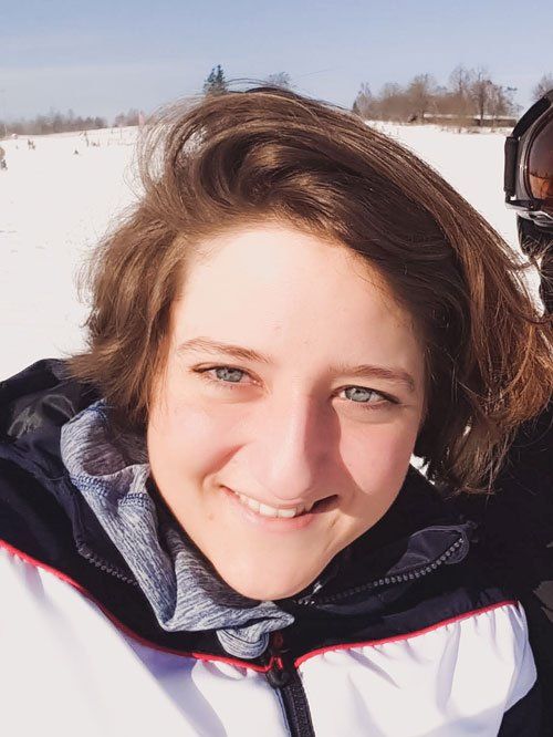 Selfie von Steffi, die im Schnee sitzt und in die Kamera lächelt