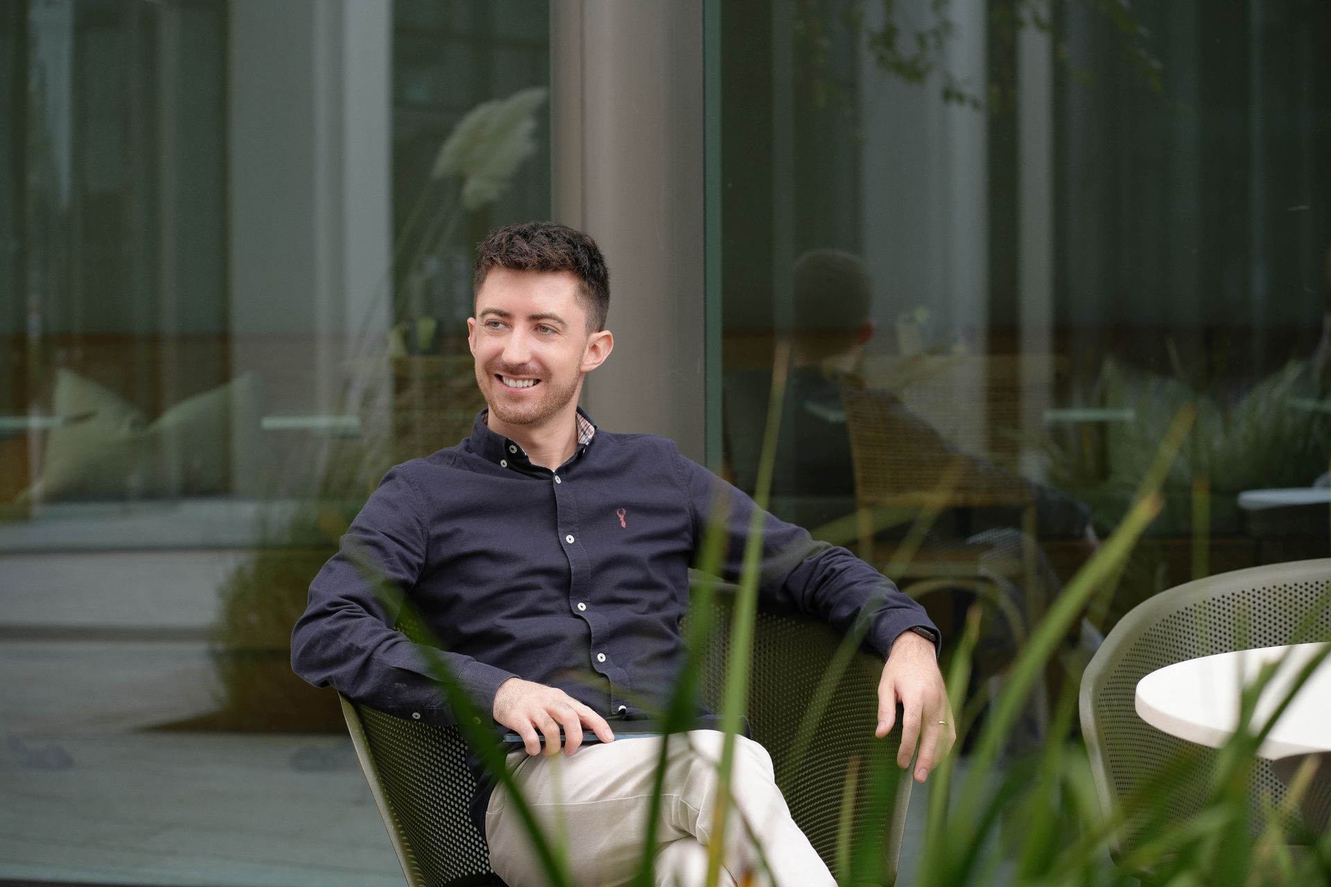 Ciaran Barry sitting in a Chair smiling and writing his blog