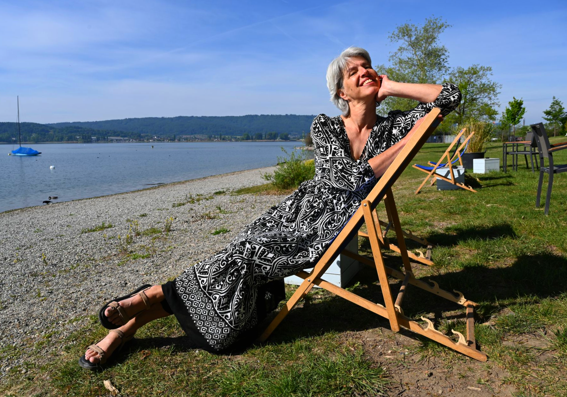 Jetzt ist das Wetter, um im schicken Kleid von MONARI am See zu sitzen.