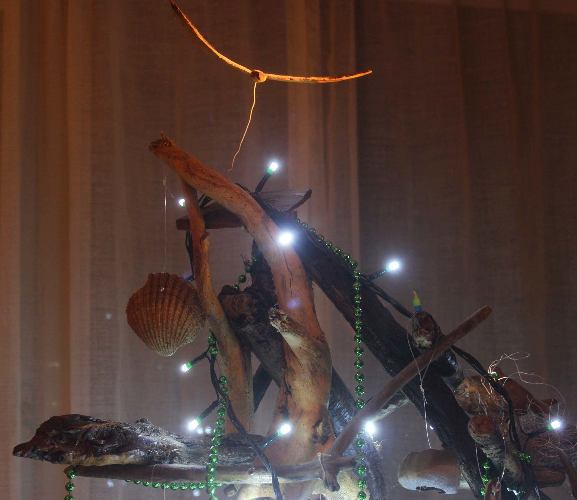 Ochre Pengelly's driftwood beach tree A christmas beach tree decorated and lit, swooping bird on top made by Ochre Pengelly artist character in author L A Kent's  Inspector DI Treloar best cornish crime thriller series set in cornwall. They are British, English, police procedurals or murder mysteries.