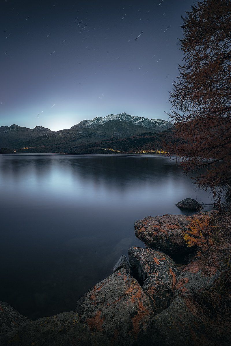 Ein Bergsee mit felsigem Vordergrund bei Nacht, Schweiz