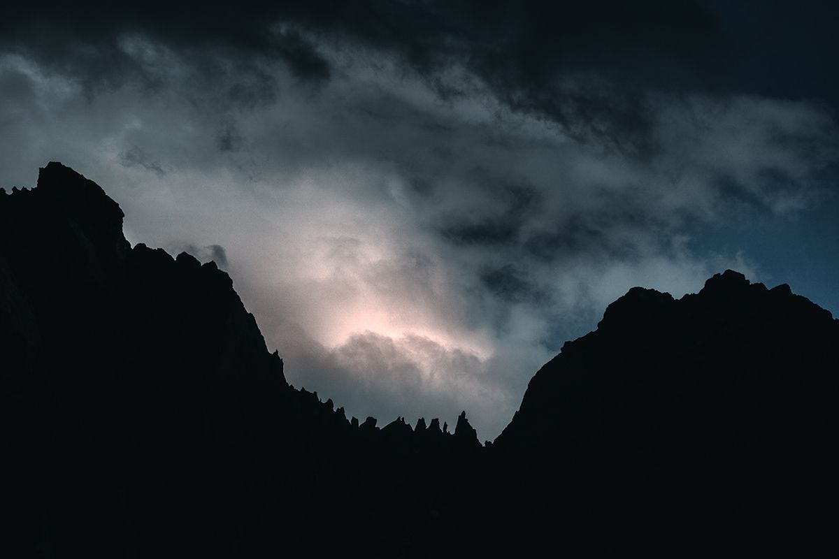 Markante Berggipfel bei Nacht und Gewitter in der Ferne, Dolomiten