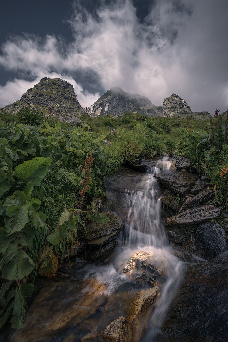 Drei markante Berggipfel mit rauschendem Bach im Vordergrund, Großer Sankt Bernhard Pass, Italien