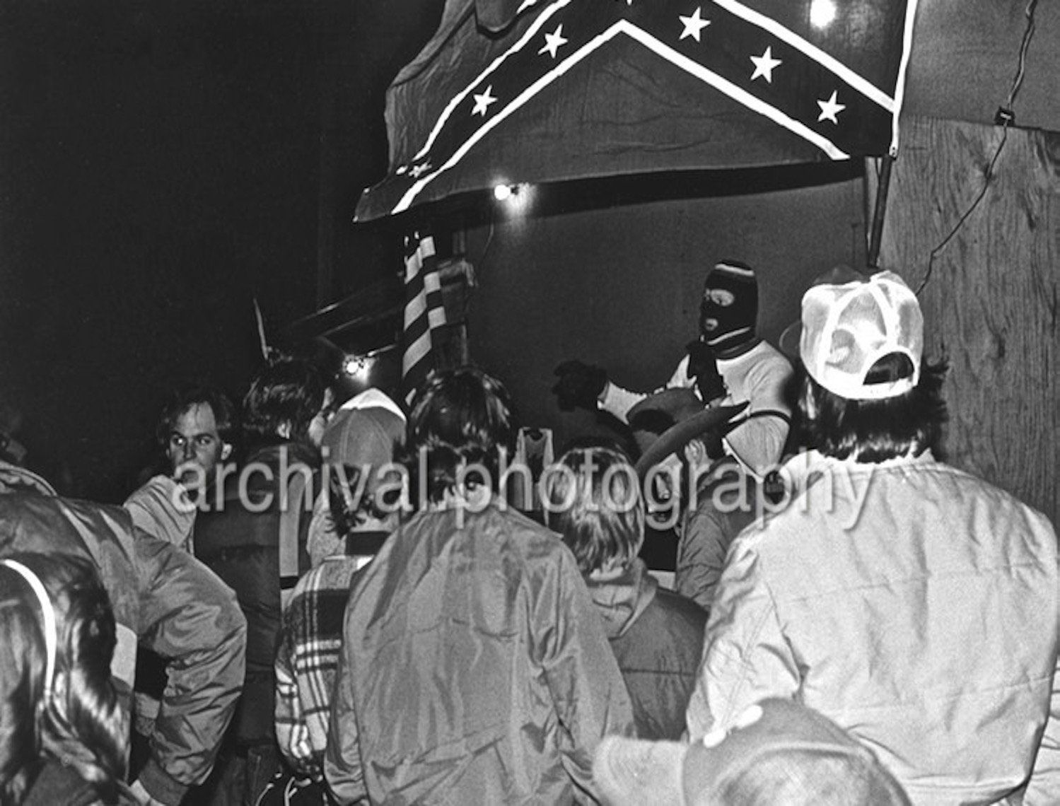 Ku Klux Klan - MASKED KKK member speaking TO FELLOW KLANSMEN WITH CONFEDERATE STARS AND BARS FLAG IN ABOVE
