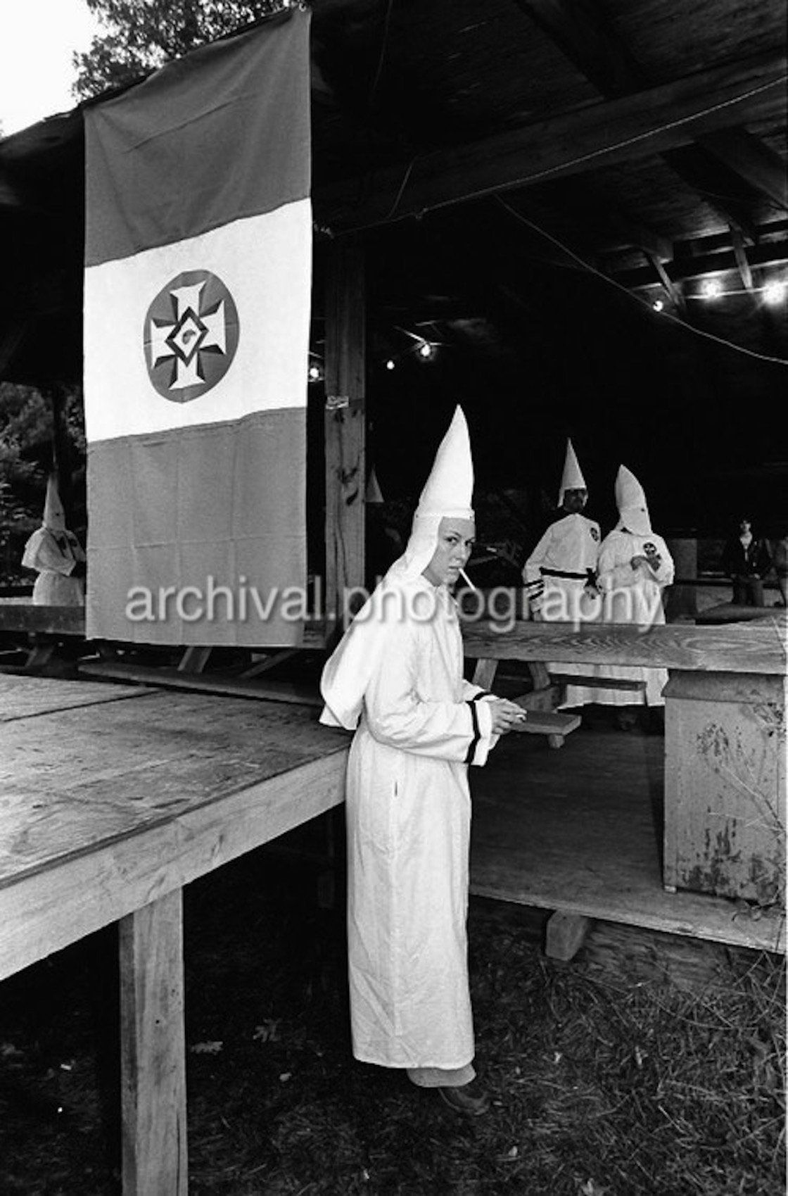 Ku Klux Klan - Female KKK member smoking a cigarette IN FRONT OF KKK FLAG