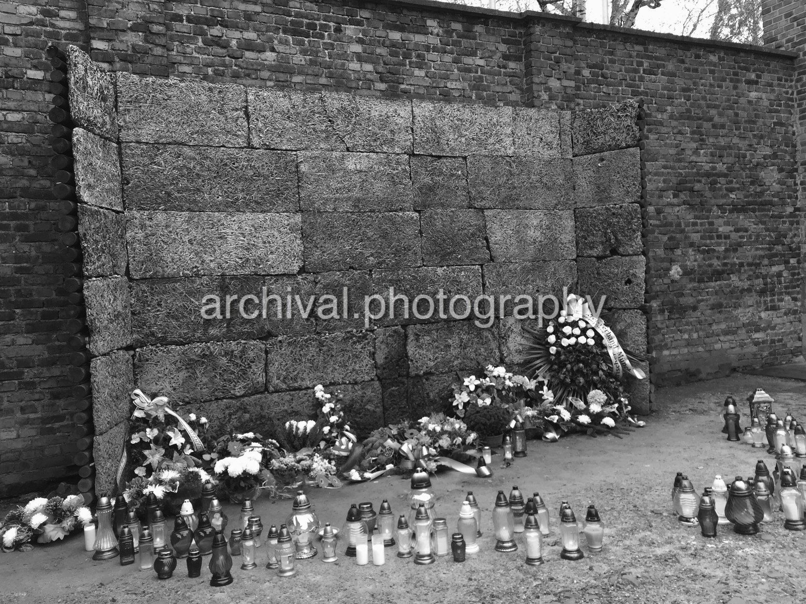 EXECUTION WALL - FIRING SQUAD WALL - Flowers and candles memorial outside of wall - Auschwitz Concentration Camp -