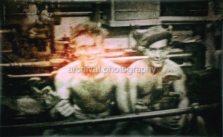Two soldiers with shirts off holding large wrenches