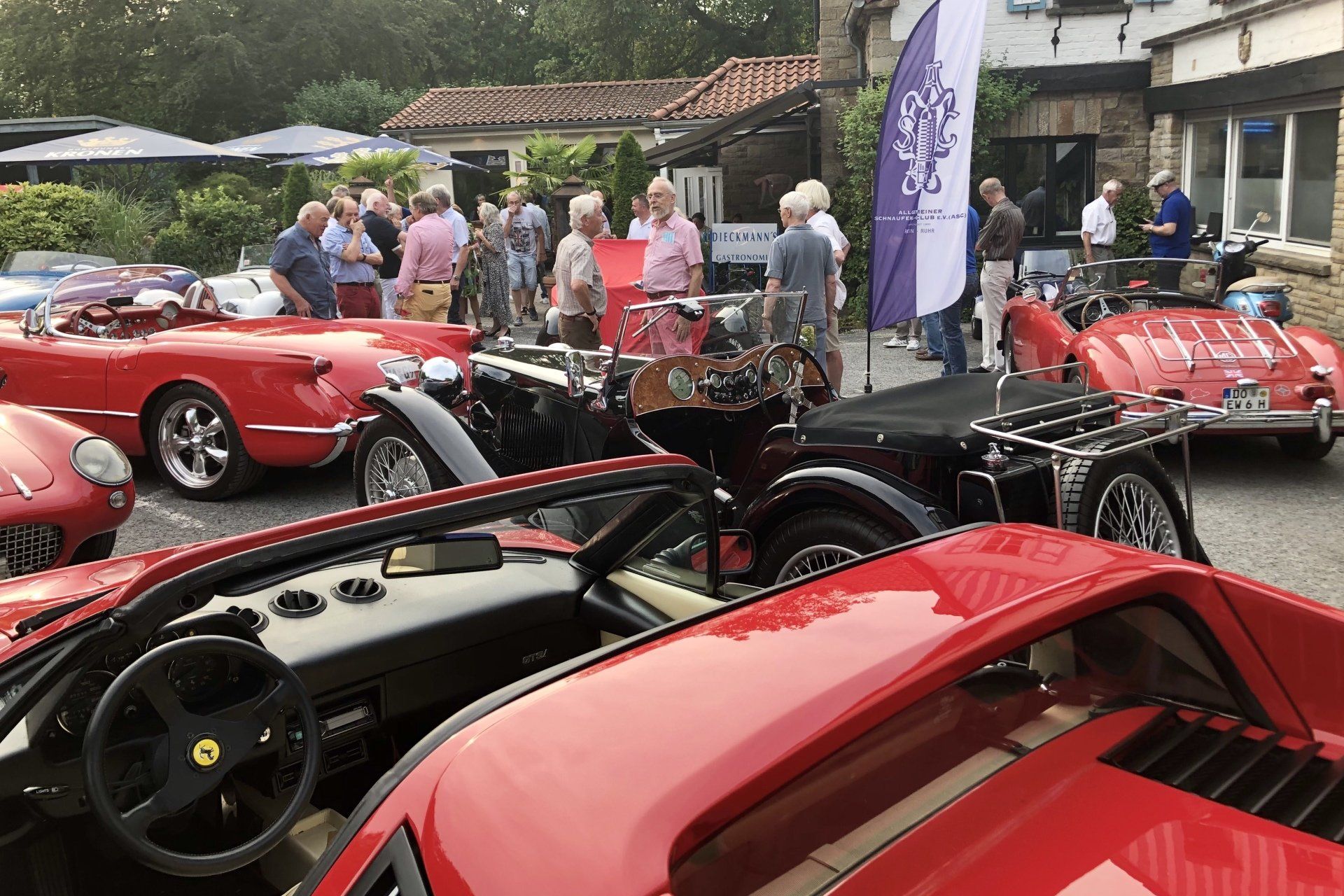 Vier rote Sportwagen Oldtimer um einen schwarzen MG
