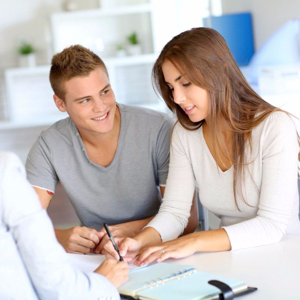 2 Junge Menschen, welche etwas unterschreiben und dabei glücklich aussehen