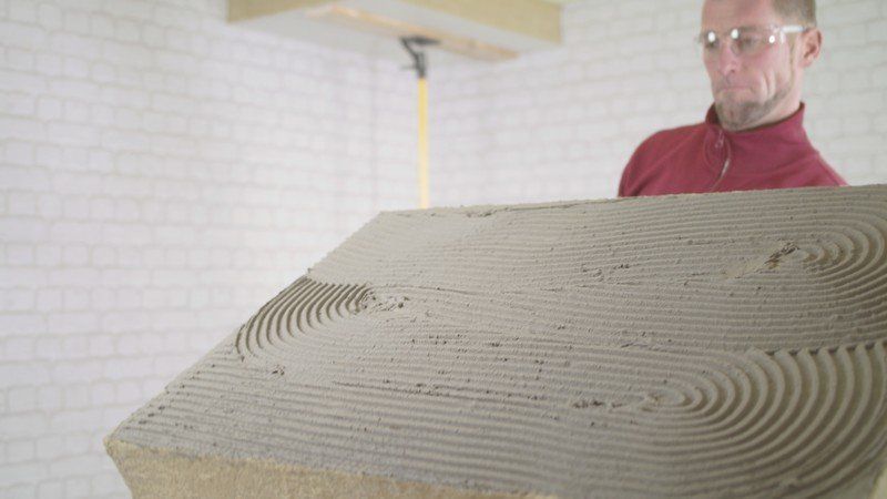 Steinwollplatten werden gegen die Kellerdecke geklebt; Isolierung für Deckendämmung