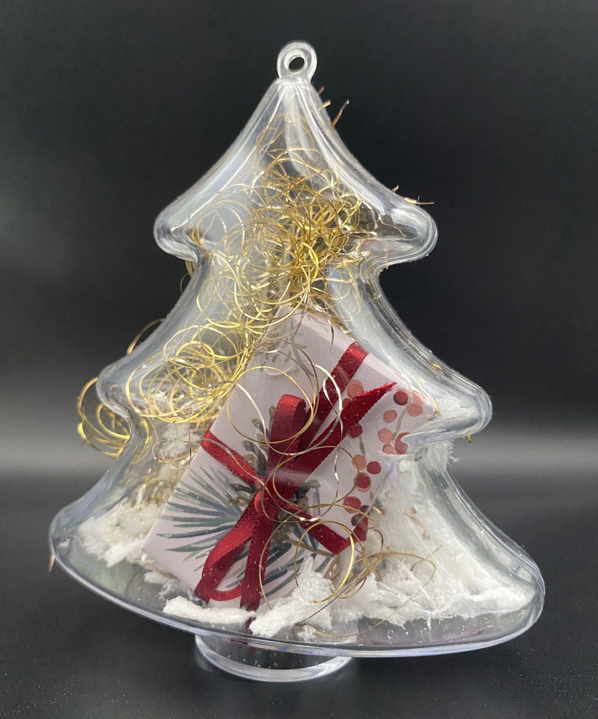 Alternativtext: Ein eleganter Tannenbaum aus Acrylglas, gefüllt mit festlichem Weihnachtsschmuck. Die transparente Struktur des Baumes lässt den glitzernden Inhalt in verschiedenen Farben strahlen und verleiht der Dekoration einen modernen, stilvollen Look.