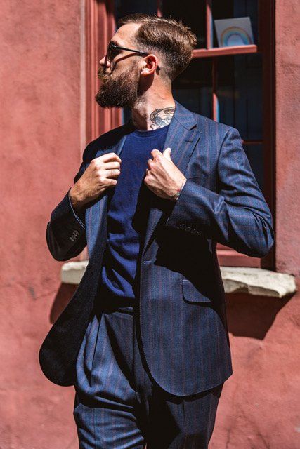 Adam Davies, founder of Adam James Bespoke, wears a sleek and lightweight blue and red striped suit to stay comfortable in the summer heat