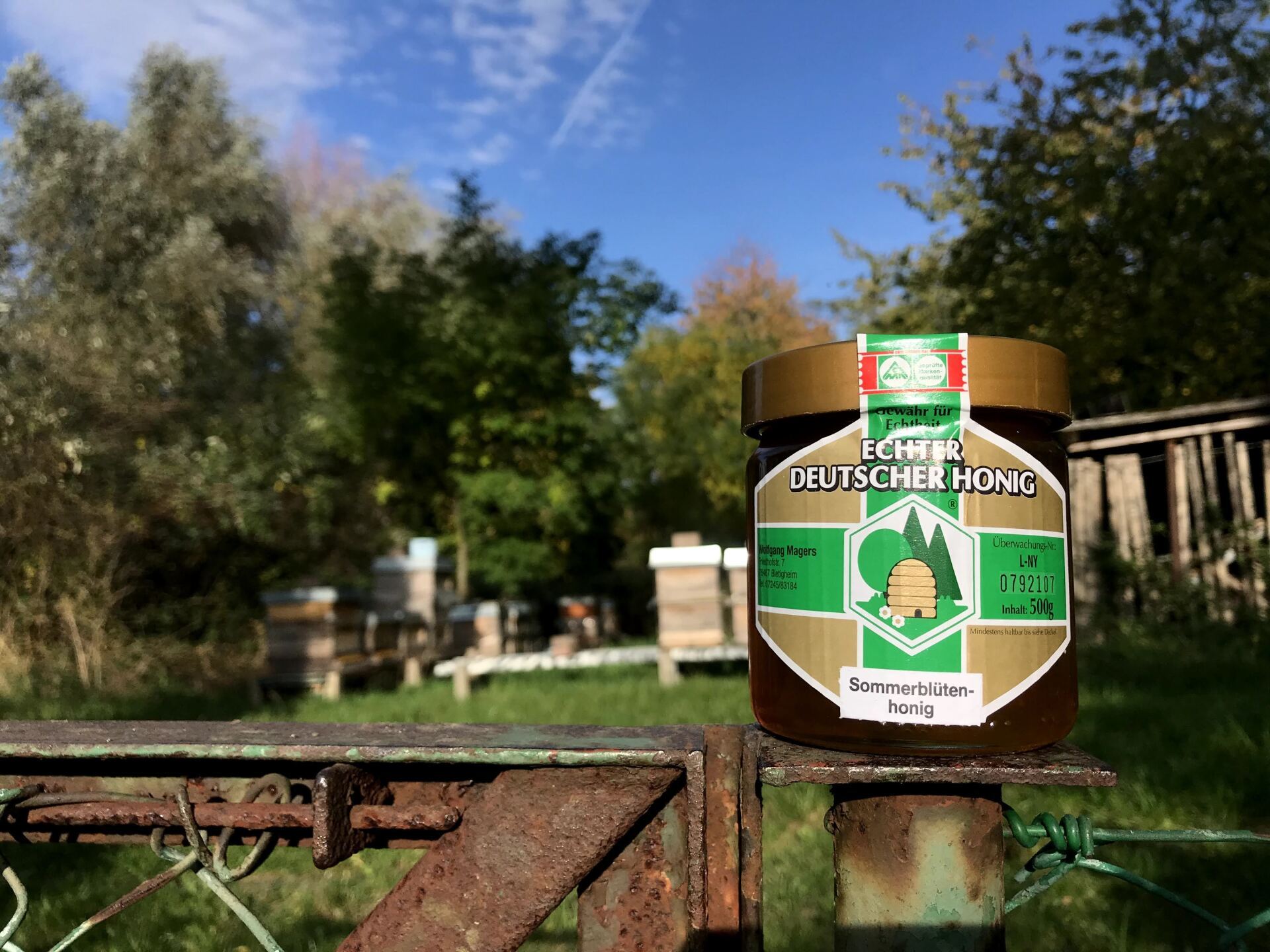Sommerblüten-Honig vom Imker Magers aus Bietigheim/Rastatt/Karlsruhe: Ein Glas Honig vor Bienenkästen und Natur