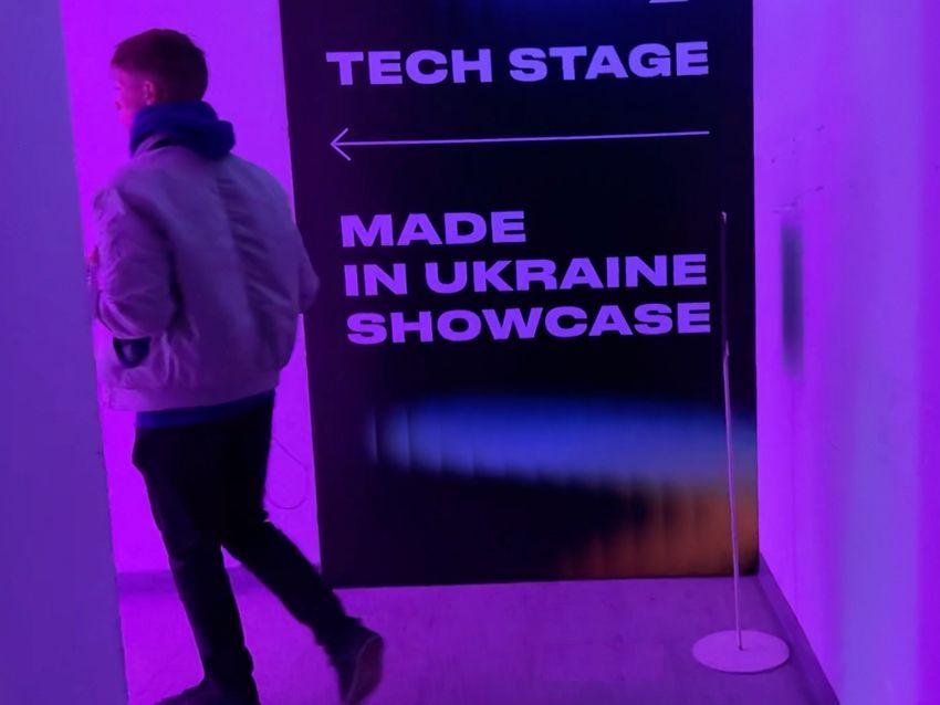 Lviv IT Arena 2025 with participant strolling through the floors of the venue along a sign providing direction to the Tech Stage