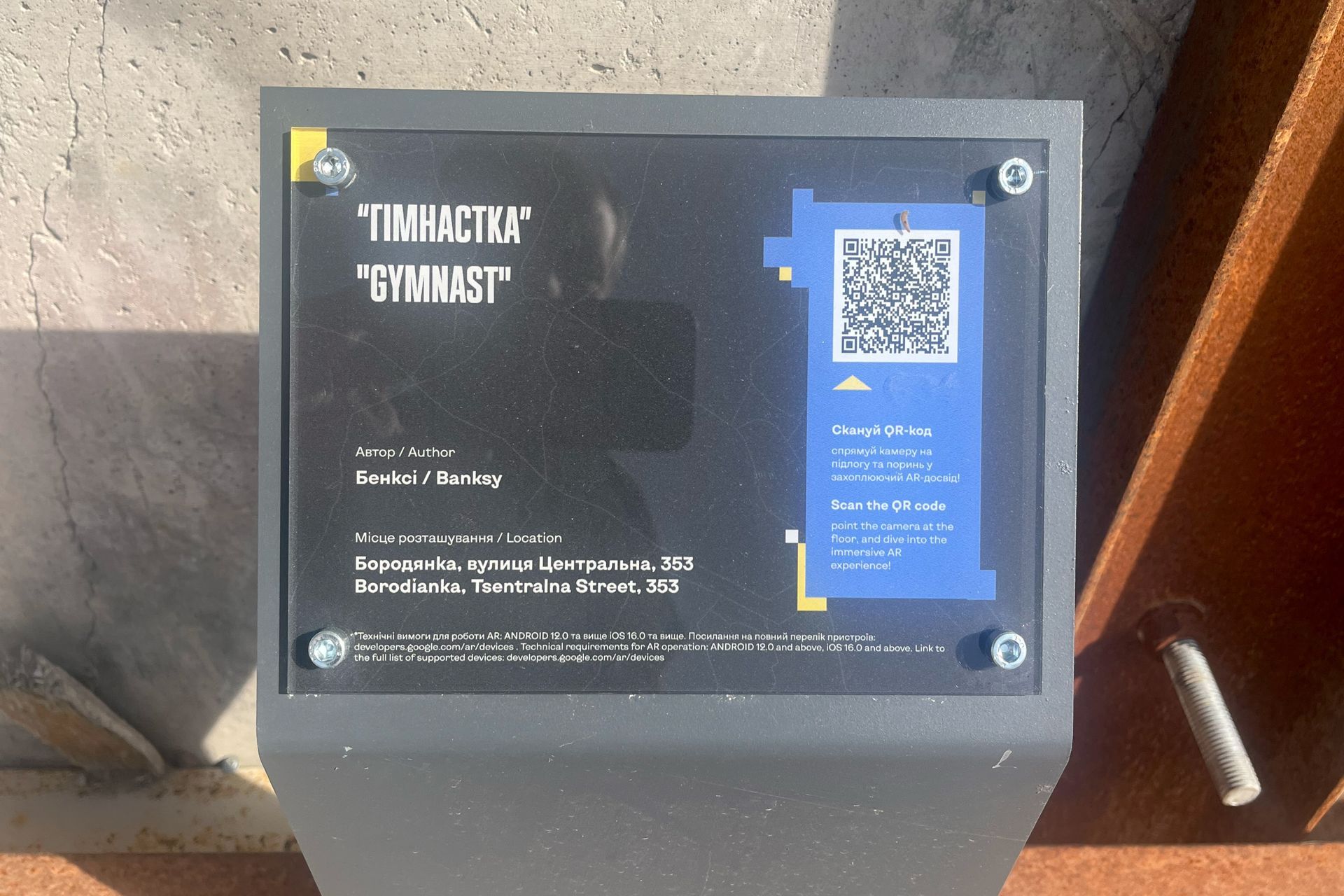 Info plaque for Banksy’s “Gymnast” artwork in Borodianka with QR code, spring 2025