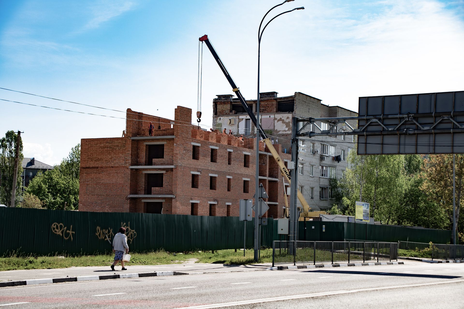 New residential building under construction in Borodianka with crane and workers, spring 2025