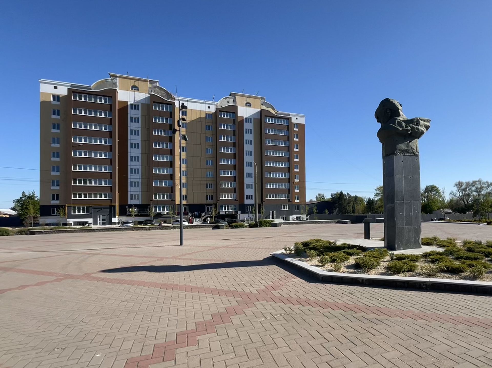 Rebuilt apartment block behind Shevchenko statue on central square in Borodianka, spring 2025