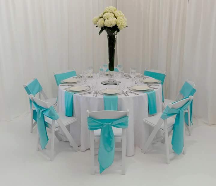 table arrangement with white chairs, aqua fabric, & yellow flowers