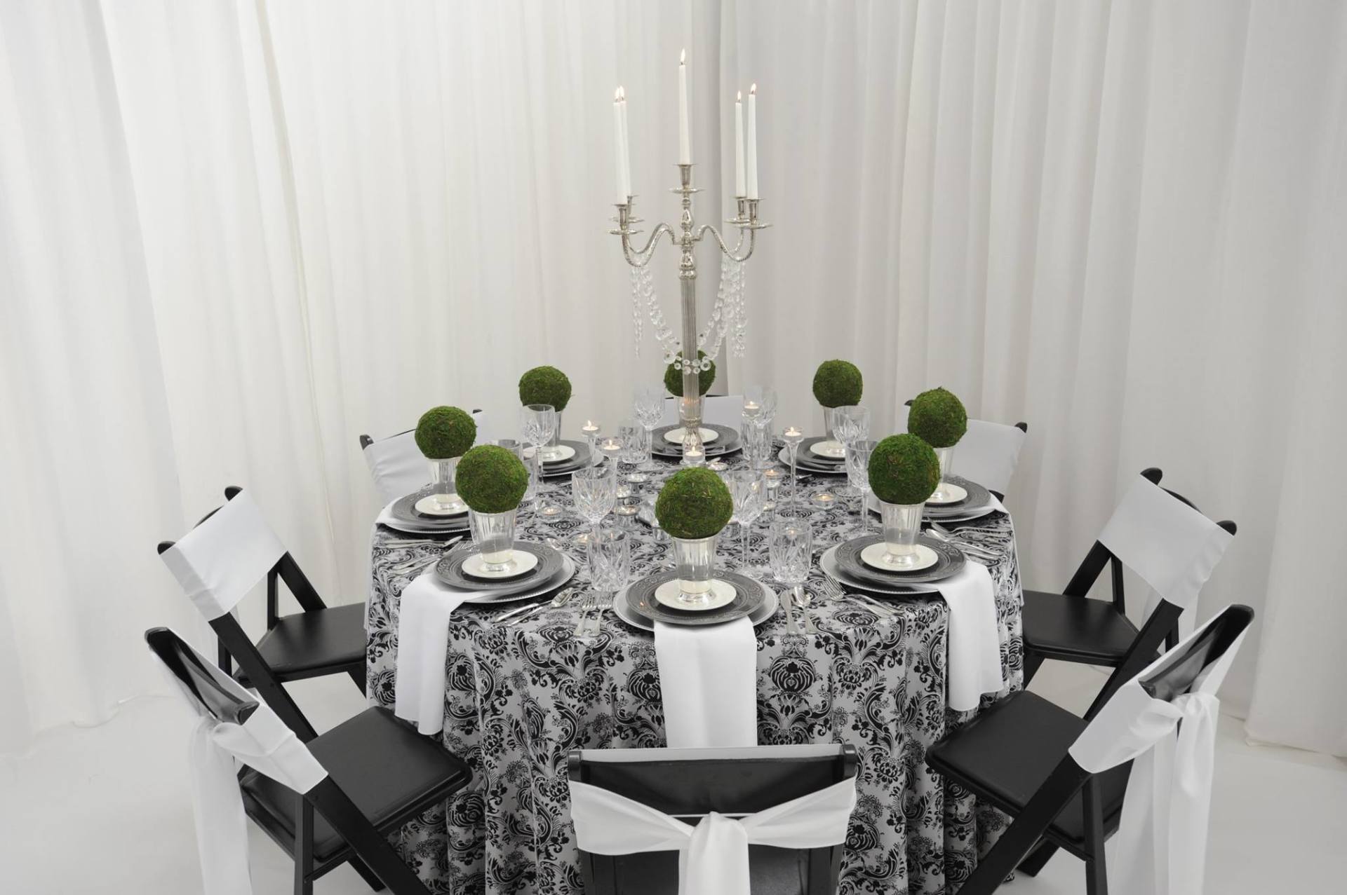 table arrangement with black chairs, white and geo fabrics, and green flowers