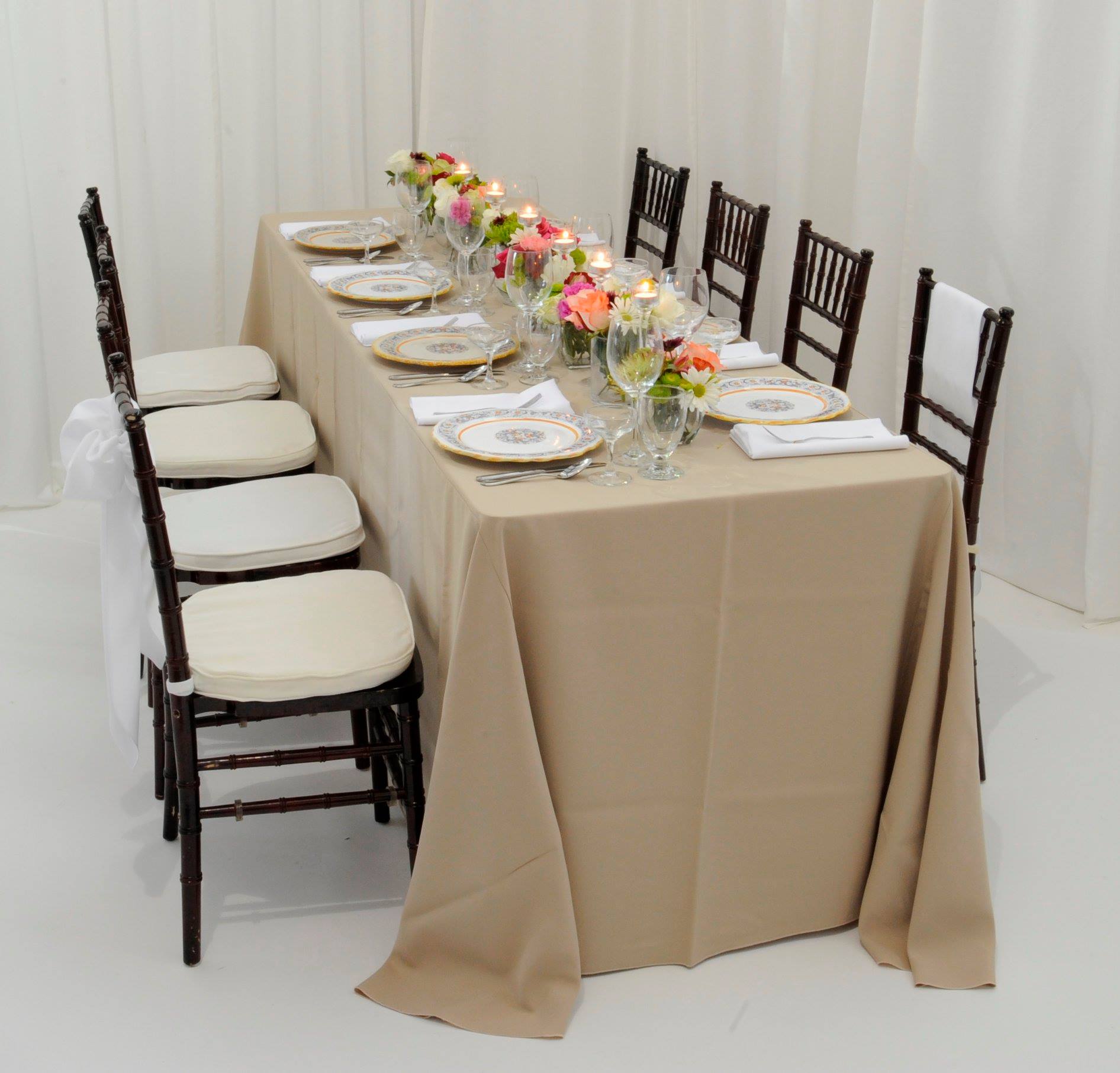 table arrangement concept with tan table cover and multi colored floral arrangements