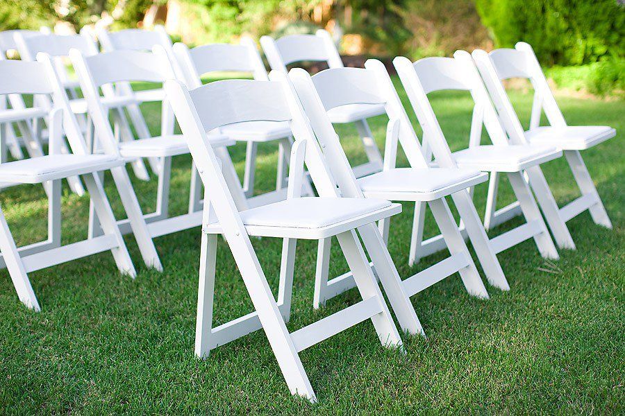 white garden resin folding chairs in rows on grass