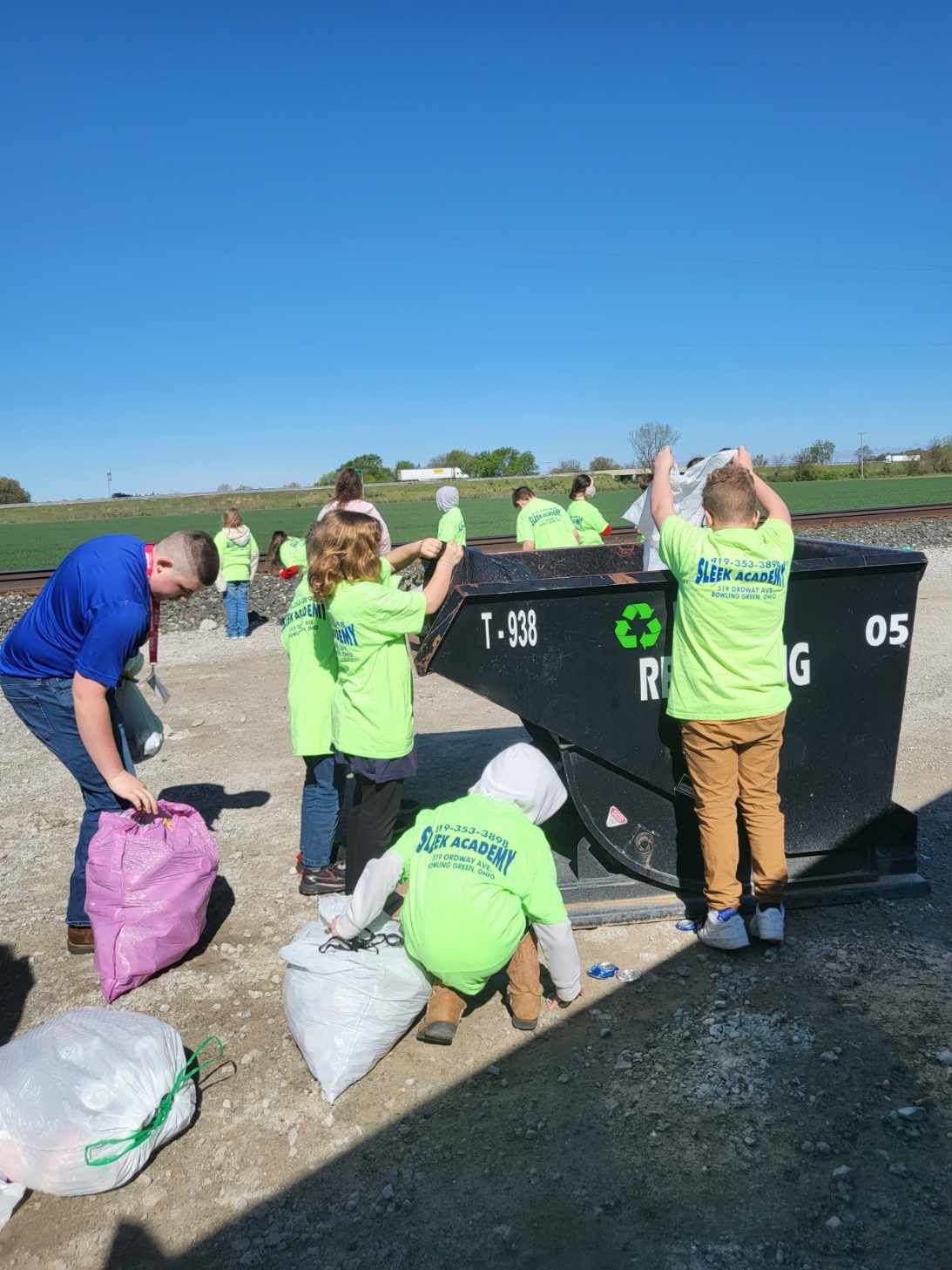 School-aged children adding recyclables to a bin.