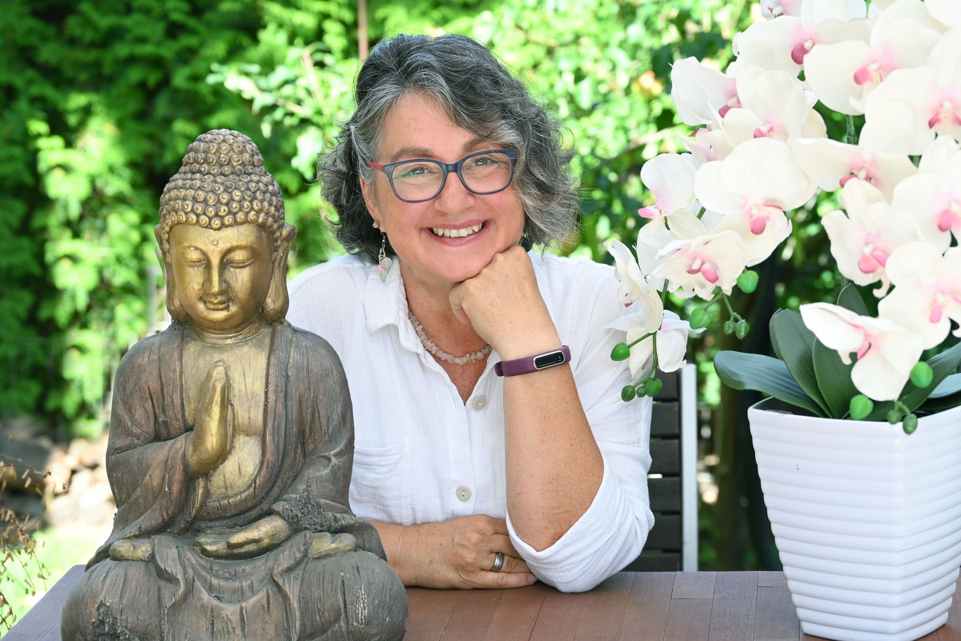 Seelenfrieden & Klarheit: Finde Deine unerschütterliche Innere Stärke durch Vertrauen und Abgrenzung. Britta Eulenfeld, lächelnd in der Natur mit Buddha und Orchidee. Symbolisiert Seelenaktivierung, Innere Stärke und Vertrauen als psychologische Beraterin
