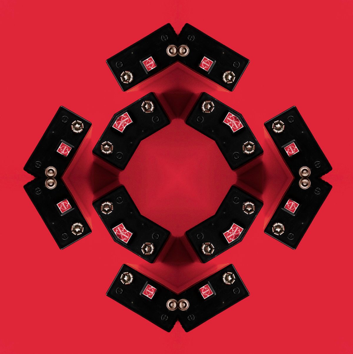 Formación concéntrica de baterías sobre un fondo rojo que representa energía y colaboración.