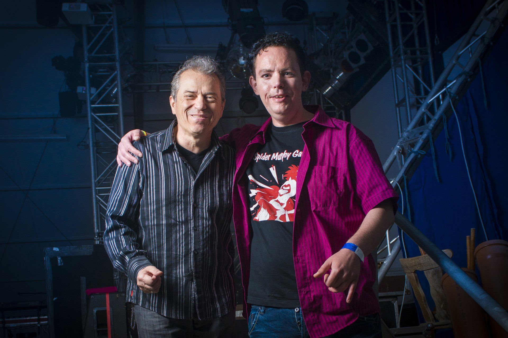 Auf diesem Bild ist ein Mann zu sehen, der Arm in Arm und sichtlich glücklich neben einem Sänger steht.