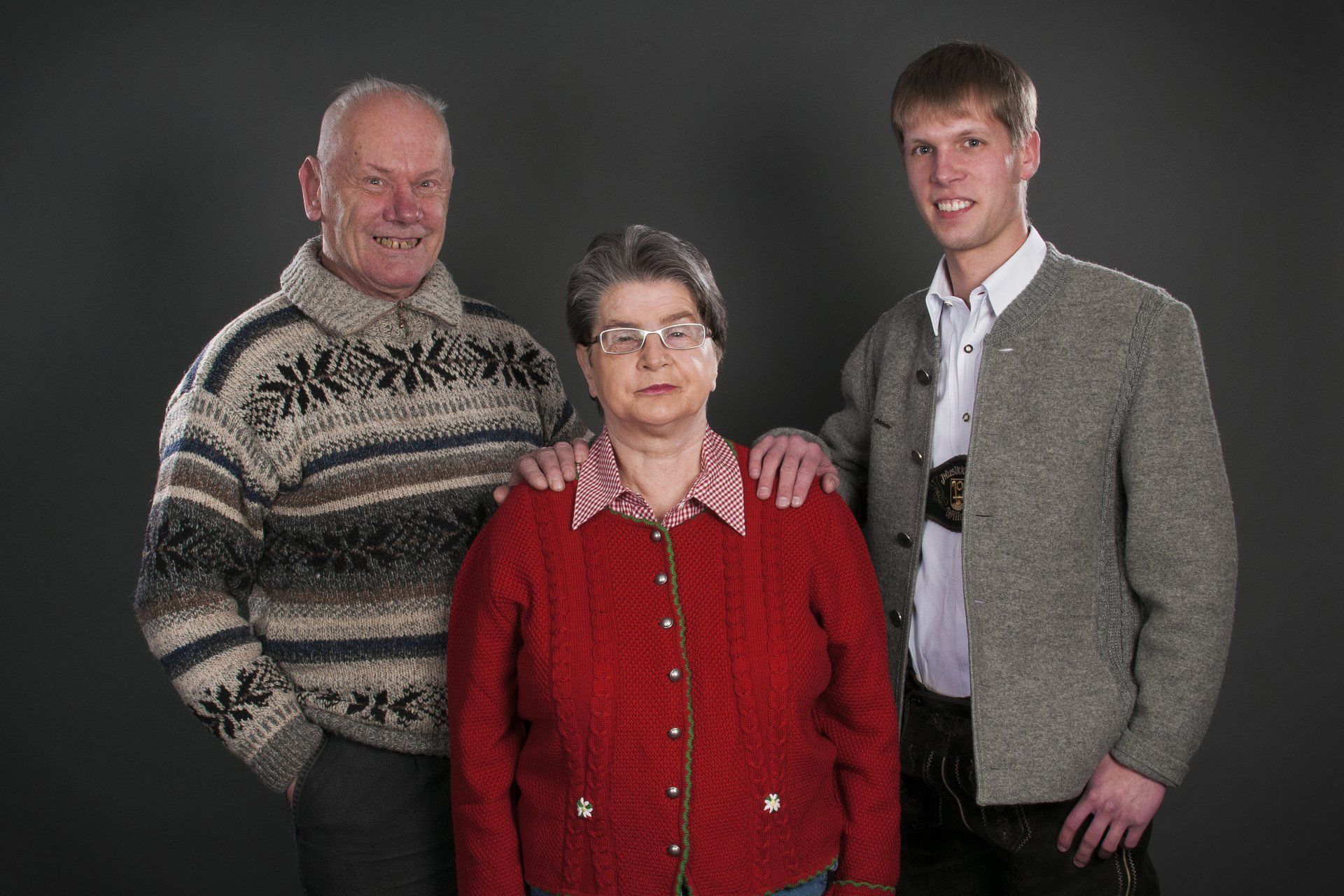 Auf diesem Bild sind eine Frau und zwei Männer zu sehen. Die Männer legen der Frau die Hände auf die Schultern.