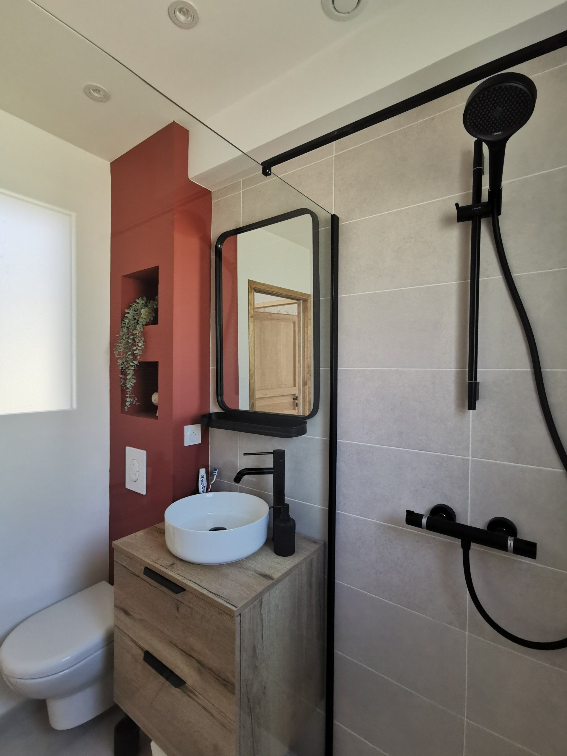 Salle de bains. Douche à l'italienne, meuble vasque bois et mur wc terracotta