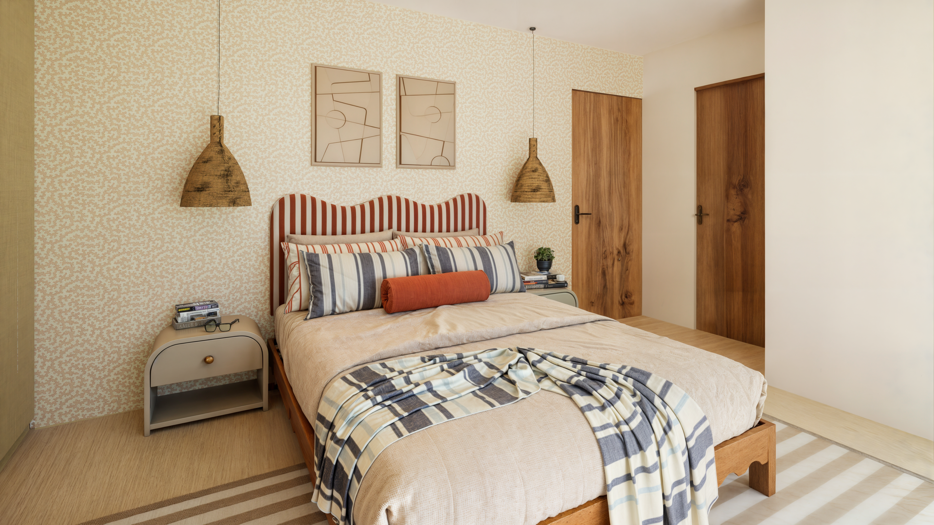 Une chambre avec une literie rayée rouge et blanche, un grand miroir, une chaise rayée orange et une commode.