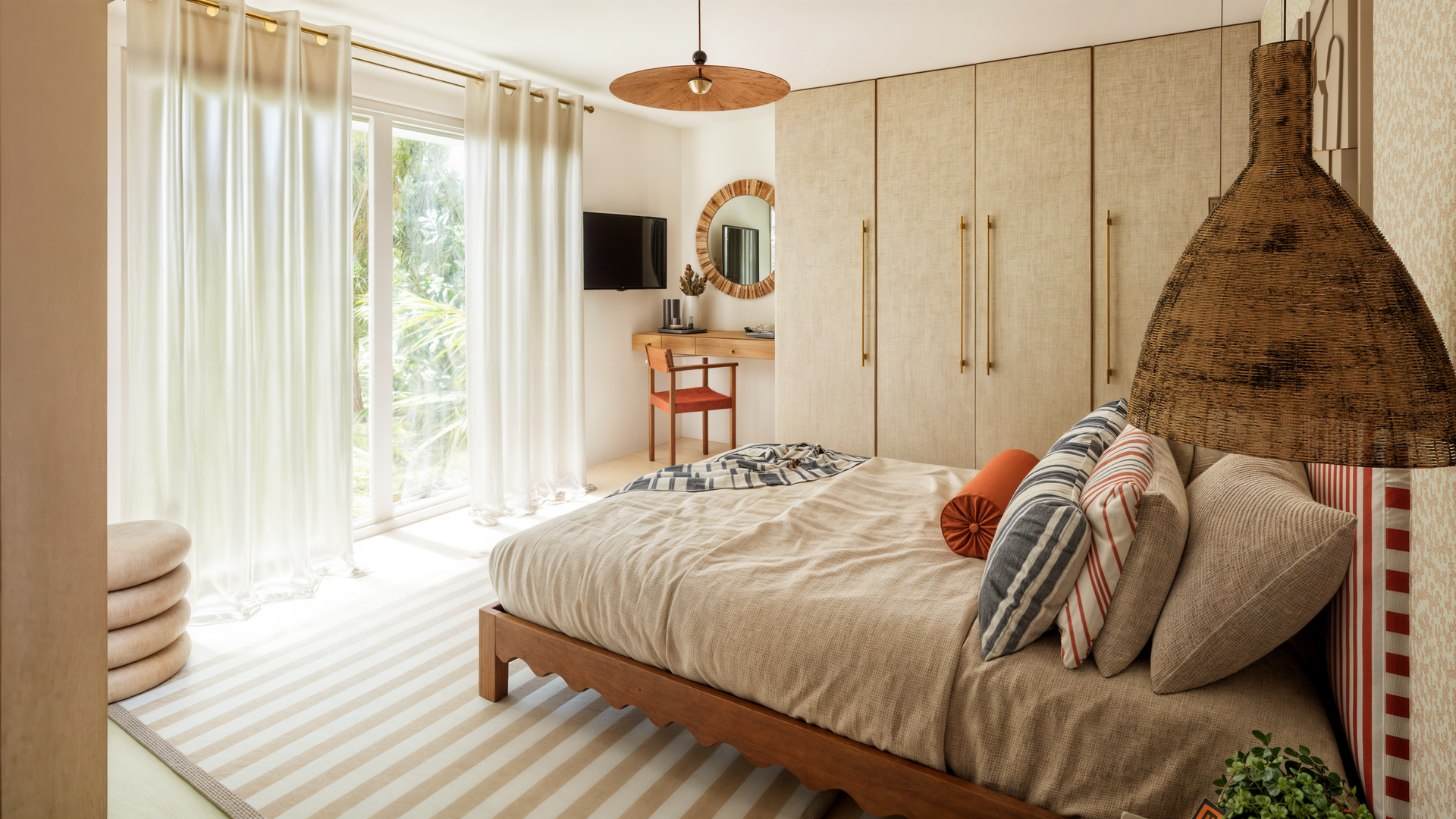 Une chambre avec une literie rayée rouge et blanche, un grand miroir, une chaise rayée orange et une commode.