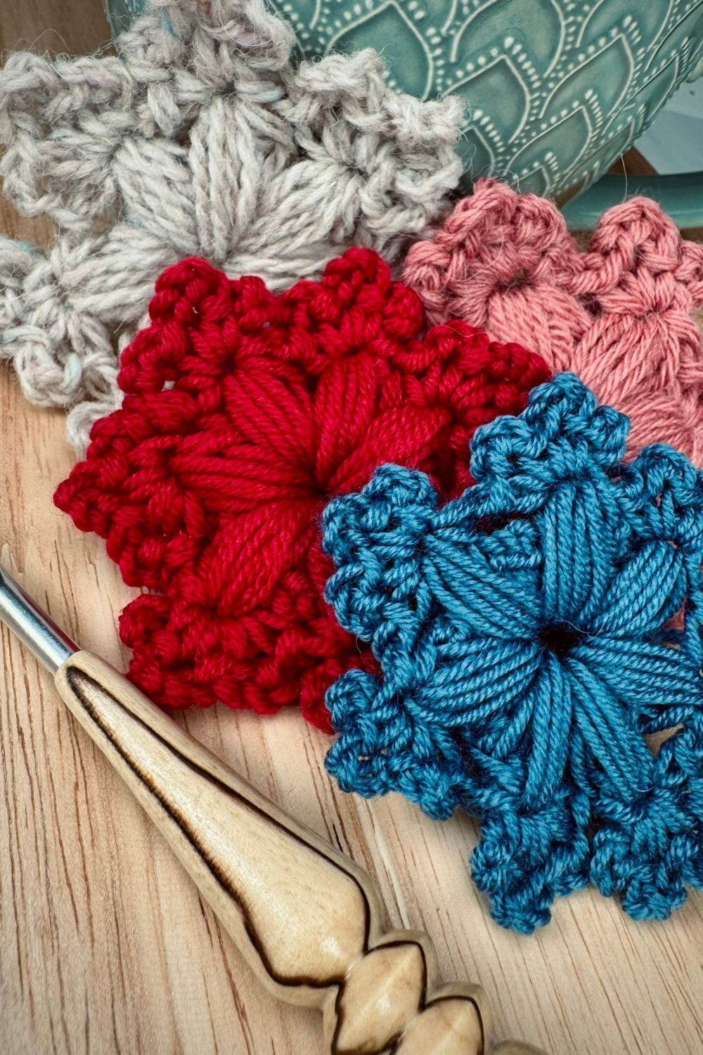 gehaekelte Schneeflocken in verschiedenen Farben auf Holztisch