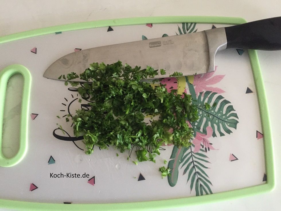 spüle die Petersilie unter kaltem, fließendem Wasser ab und schüttel sie trocken. Dann lege die Petersilie auf das Schneidebrett und entferne die Stiele. Nun kannst Du die Petersilie klein hacken.
