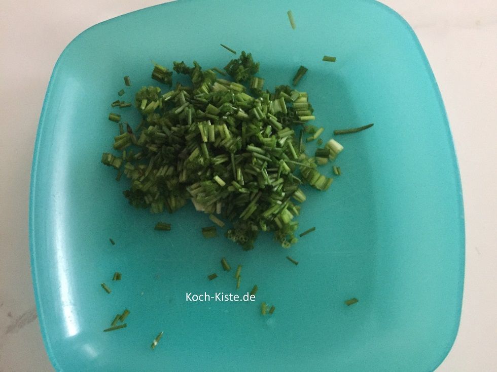spüle den Schnittlauch unter kaltem, fließendem Wasser ab und schüttel ihn trocken. Dann nehme den Schnittlauch in einen Hand und schneide ihn über dem Teller in kleine Ringe.