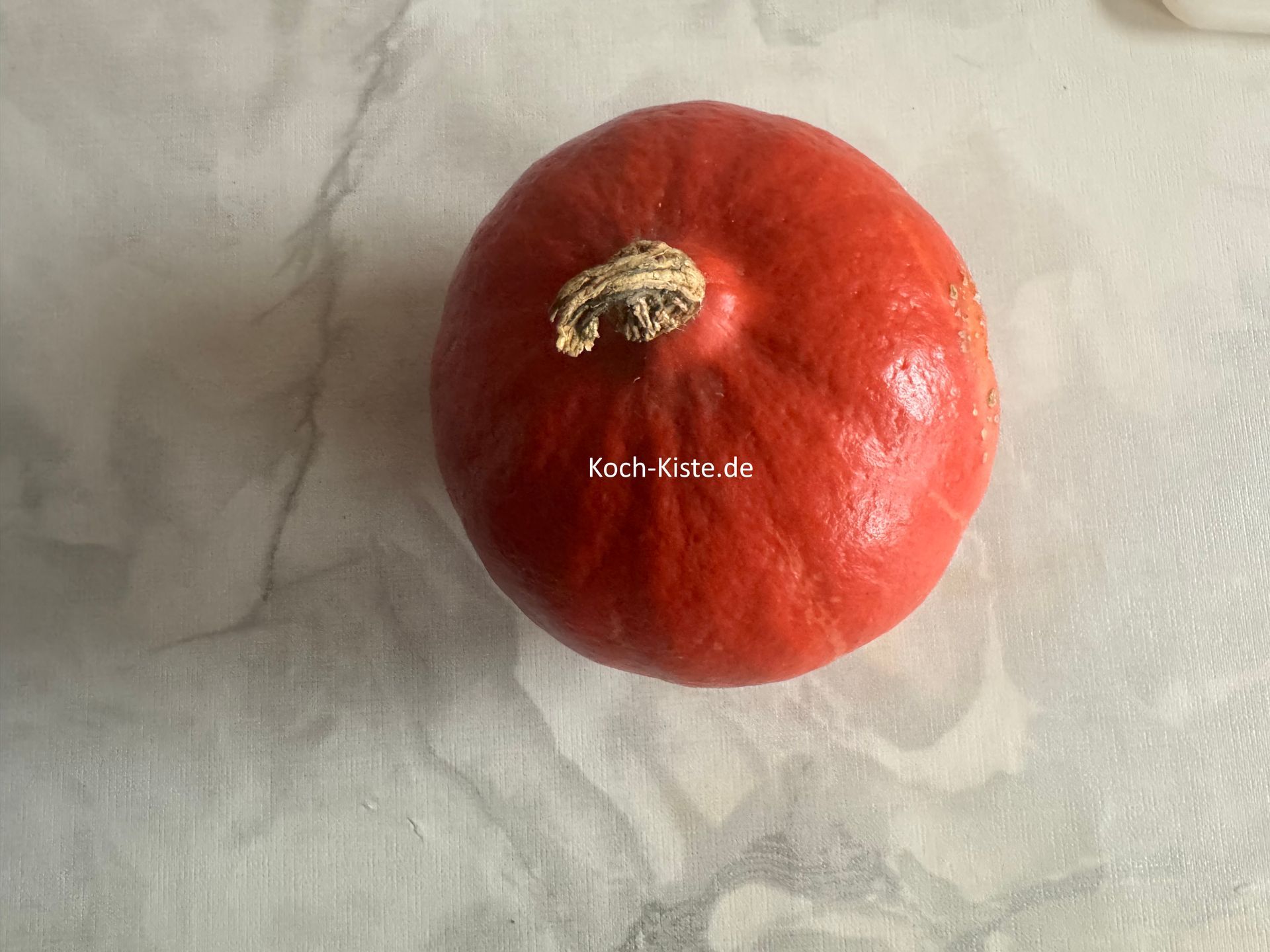 wasche den kleinen Hokkaido Kürbis unter kaltem, fließendem Wasser , trockne ihn ab und lege ihn auf die Arbeitsfläche