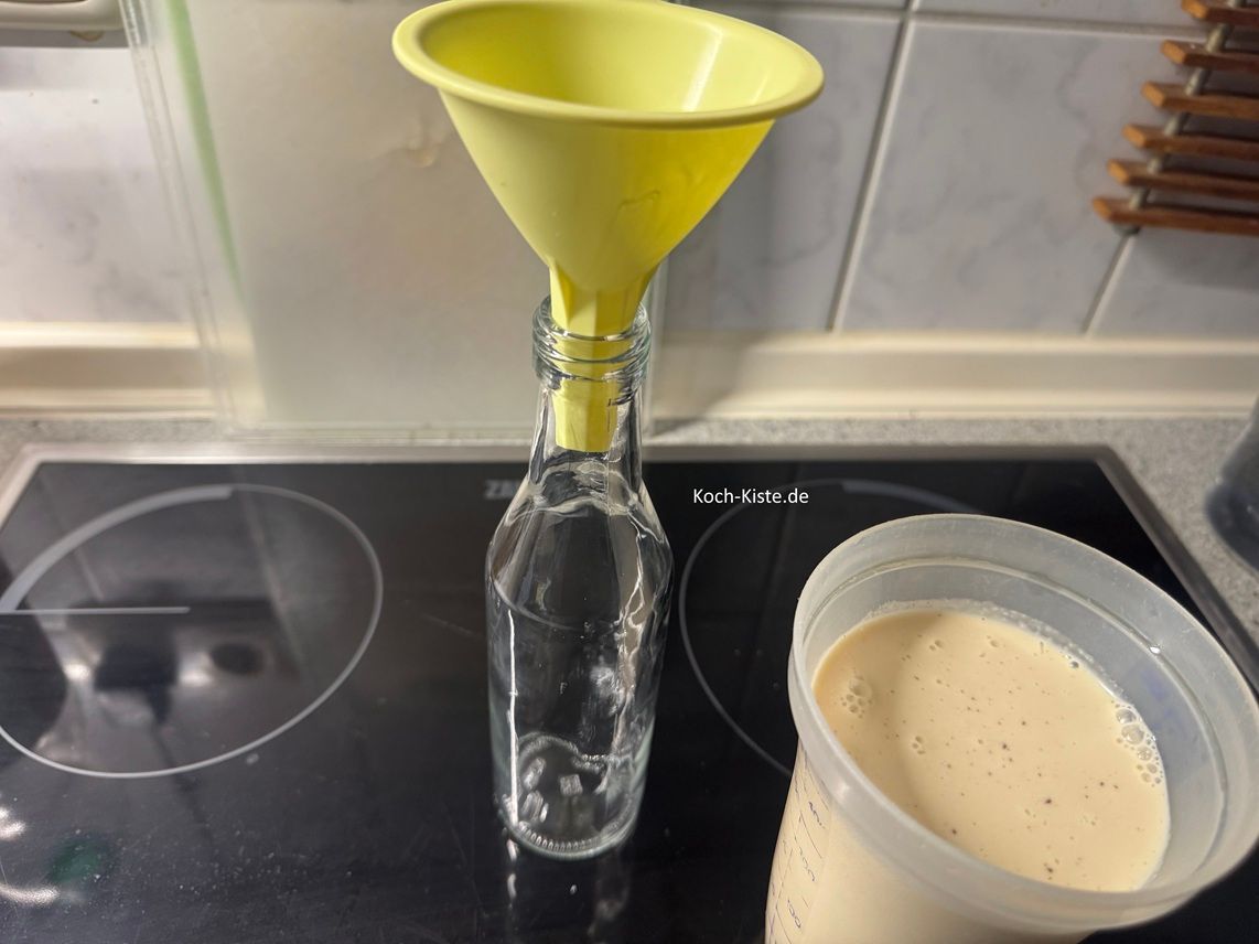 Jetzt setze einen kleinen Trichter auf eine vorbereitete Flasche und gieße den Marzipan Likör hinein. Danach fülle die anderen Flaschen.