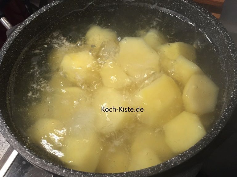 Die Kartoffeln werden geschält, halbiert, in ein Küchensieb gegeben und unter kaltem, fließendem Wasser abgespült. Dann gebe sie in einen Kochtopf und koche sie 20 Minuten gar