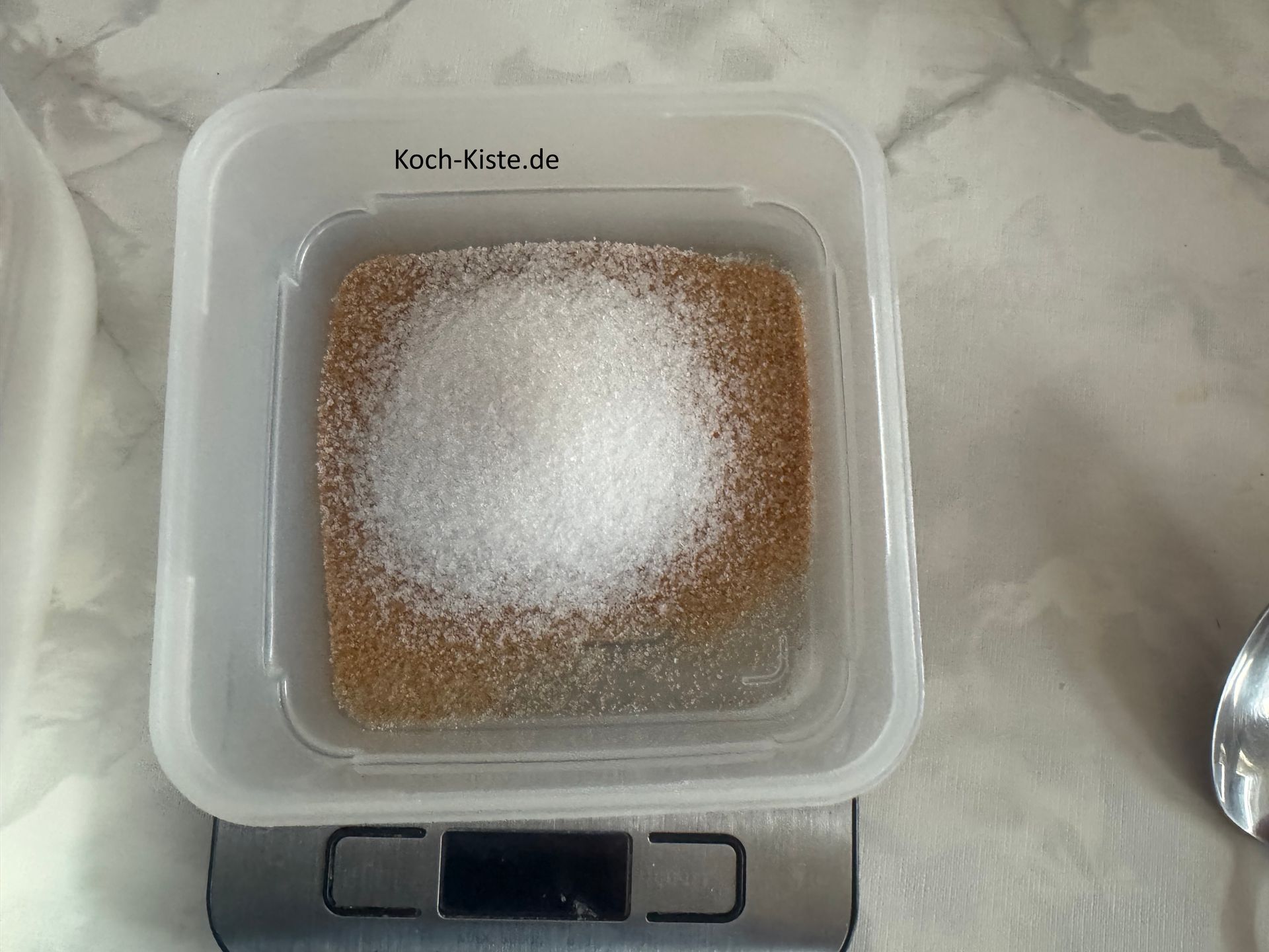 stelle eine kleine Schale auf die Küchenwaage - auf 0 und wiege 50 g braunen Zucker hinein. Stelle die Küchenwaagea wieder auf 0 und wiege 40 g Zucker ab.