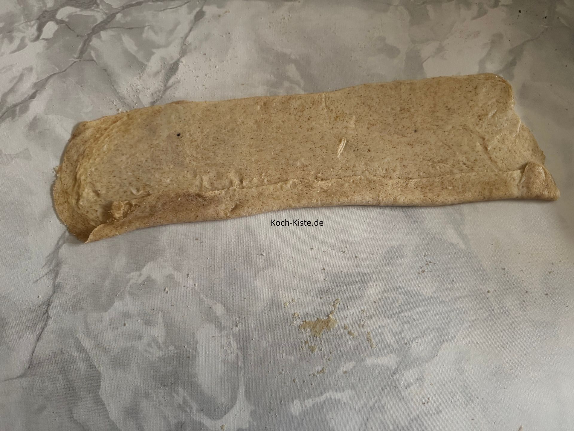 als nächstes hebe den Teig, mit deinen Daumen, von der langen Seite an und klappe ihn um.