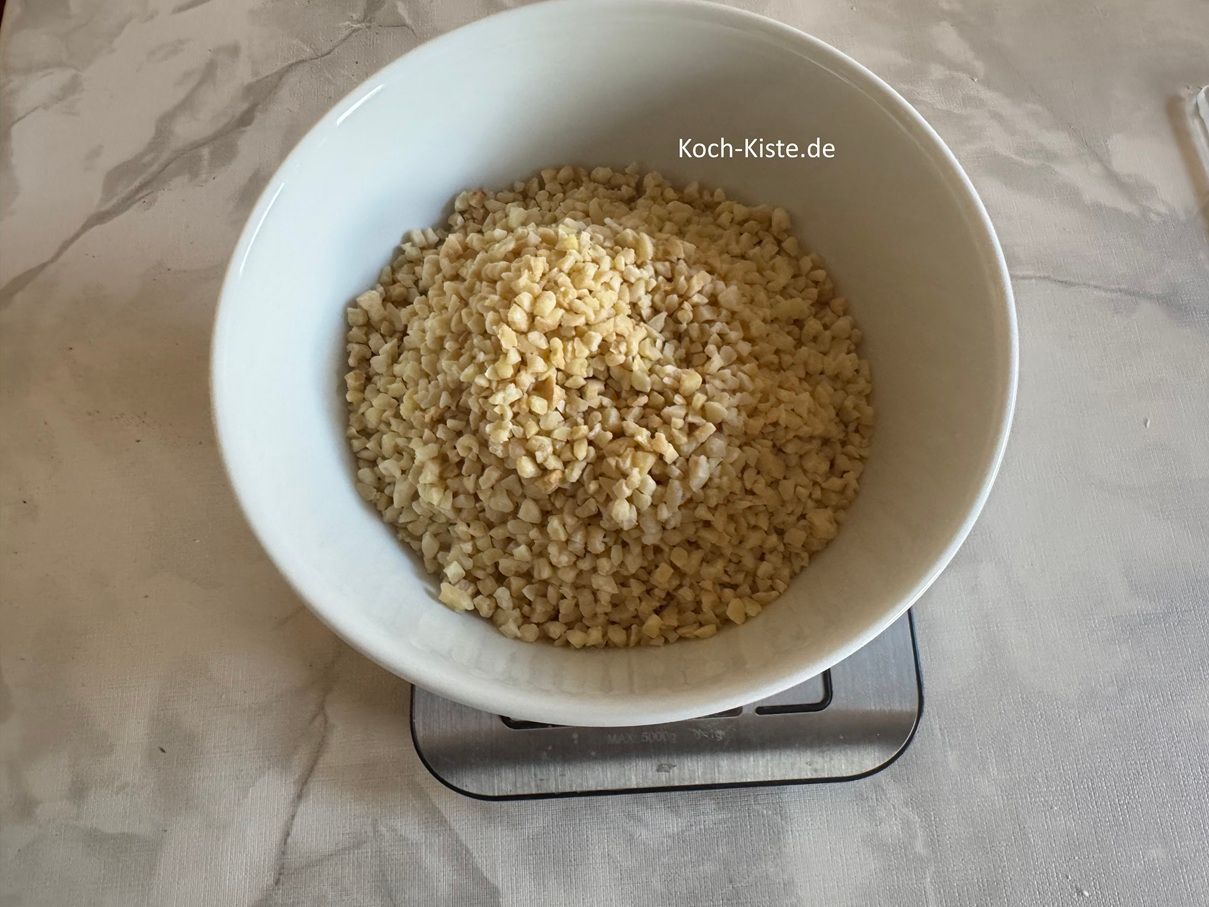 dann stelle eine Schüssel auf die Küchenwaage - auf 0 und wiege Dir 120 g (240g) gehackte Mandeln ab