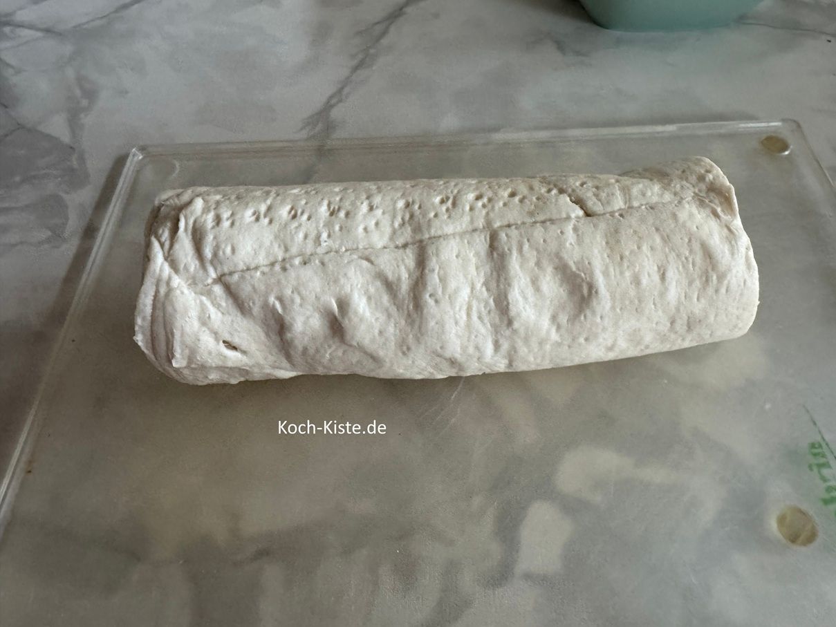 Drehe die Verpackung weiter und entnehme den Croissantteig. Lege ihn mit der Markierung nach oben auf das Schneidebrett.