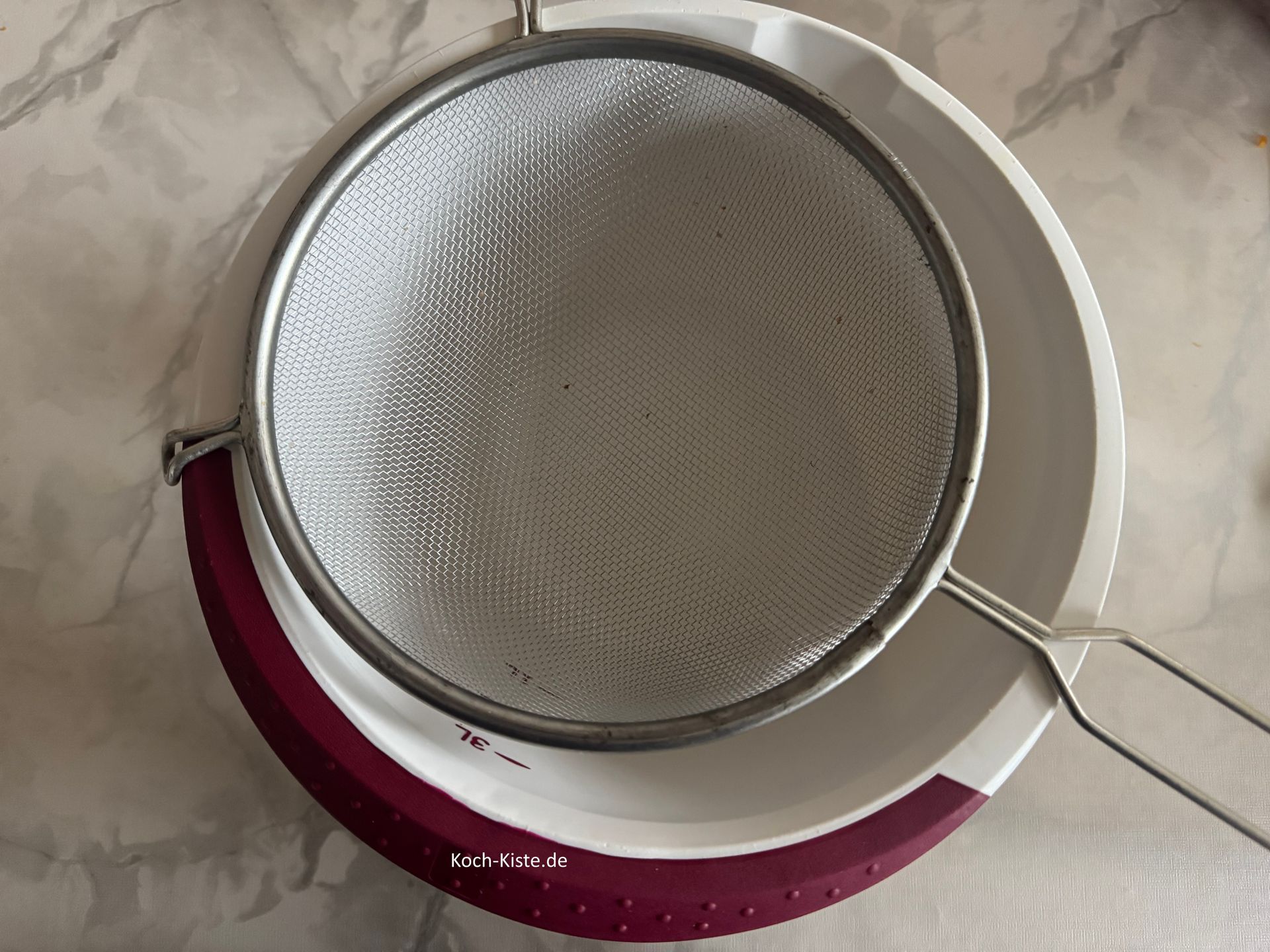 In der Zwischenzeit stelle eine Rührschüssel auf die Küchenwaage - lege ein Haarsieb drauf und stelle die Gewichtsanzeige auf 0