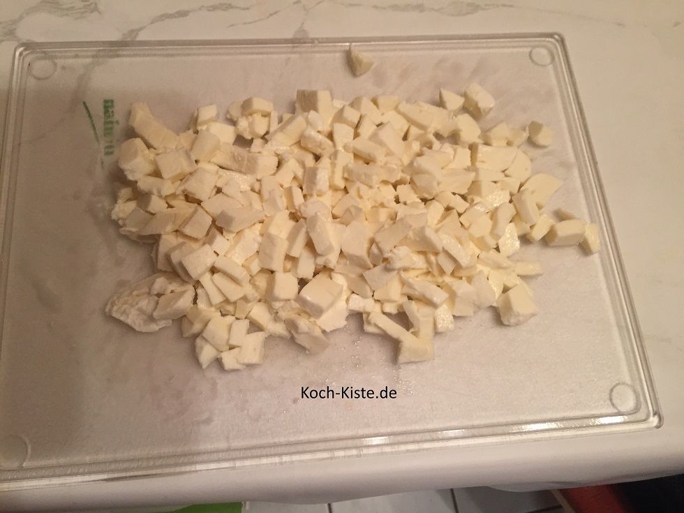 Wenn der Mozzarellakäse abgetropft ist, lege sie auf ein Schneidebrett und schneide sie erst in Scheiben, dann in Streifen und zum Schluss in kleine Stücke .